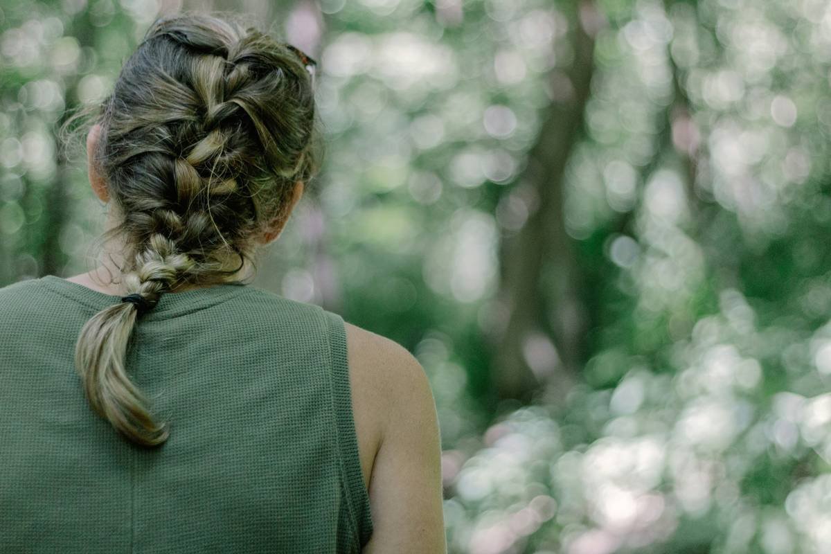 Side-by-side infographic: ponytail vs. braid during exercise showing tension points on scalp and hair movement