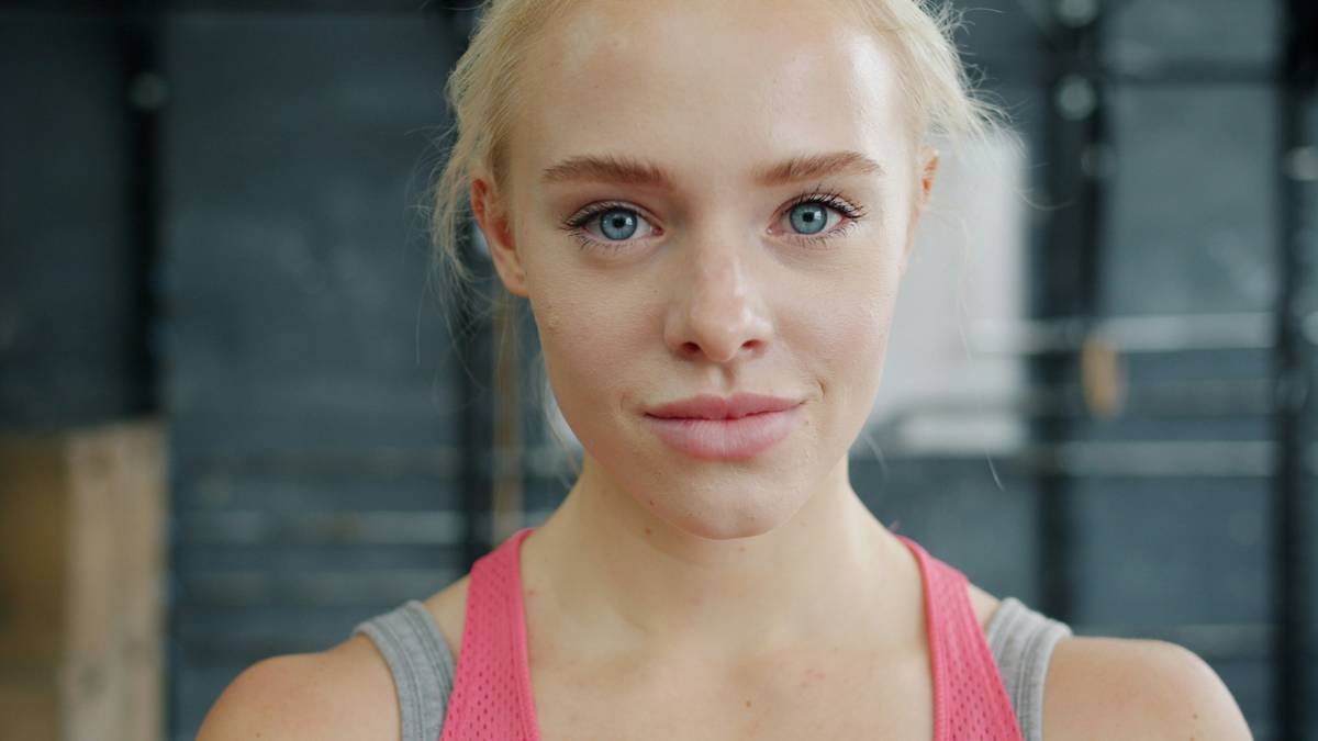 Close-up portrait of young woman blonde in sportswear standing in gym and looking at camera. Emotions, sporty people and healthy lifestyle concept.