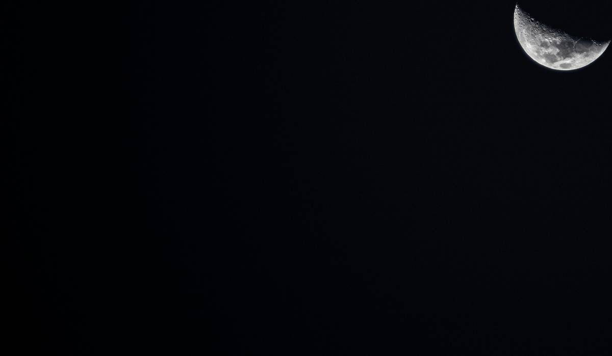 This photograph focuses on the waxing crescent moon against the vastness of the night sky, highlighting the moon's cratered surface with great detail and contrast, embodying the tranquility of the cosmos.