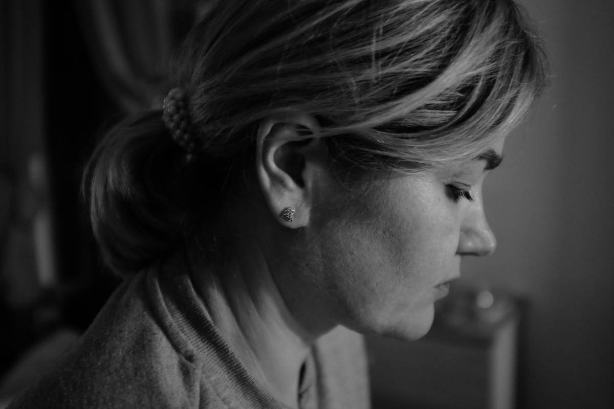 Woman looks down in thought, in grayscale.