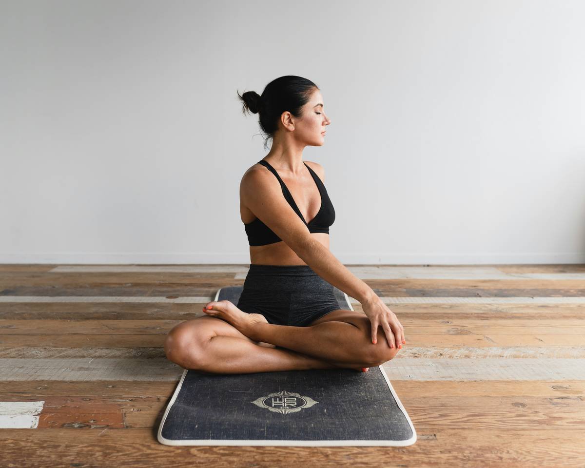 Close-up of workout hair yoga clip securing low twisted bun on woman in plank pose